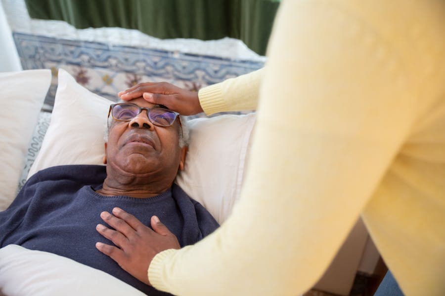 Cuidador assistindo idoso em casa com equipamentos hospitalares